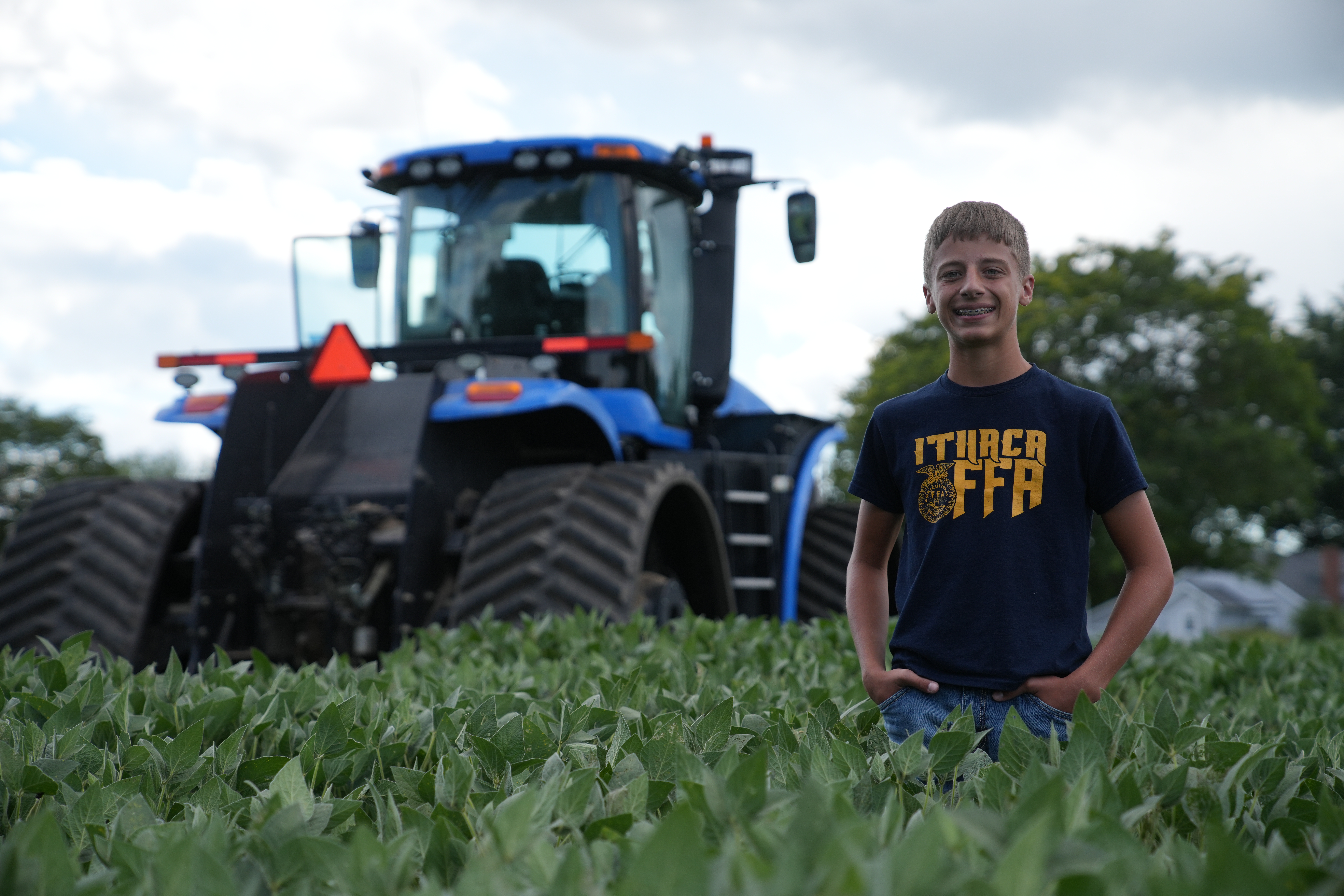 ithaca ffa student standing in the land lab by a tractor
