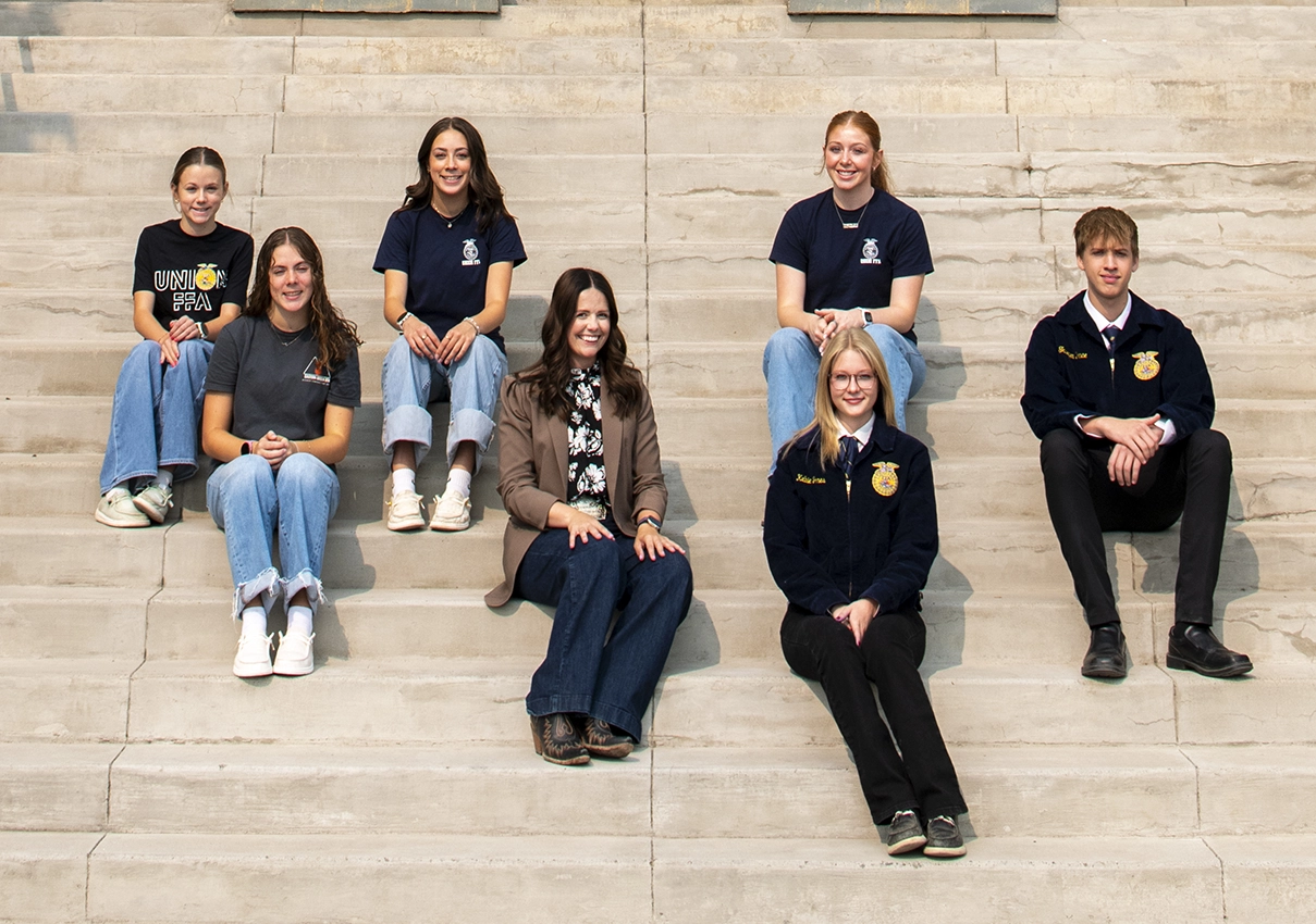 Union FFA students and their advisor sitting on the front steps of their school.